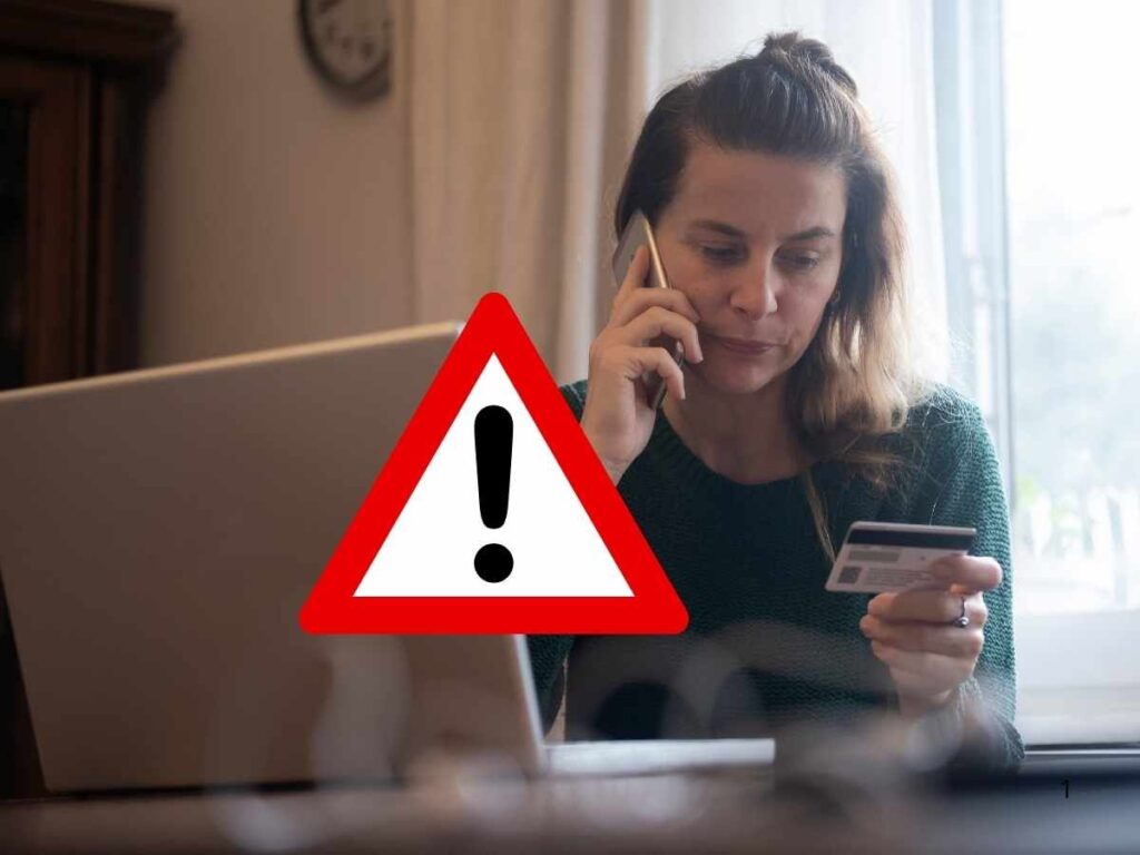 donna al telefono davanti pc con carta elettronica in mano, segnale pericolo